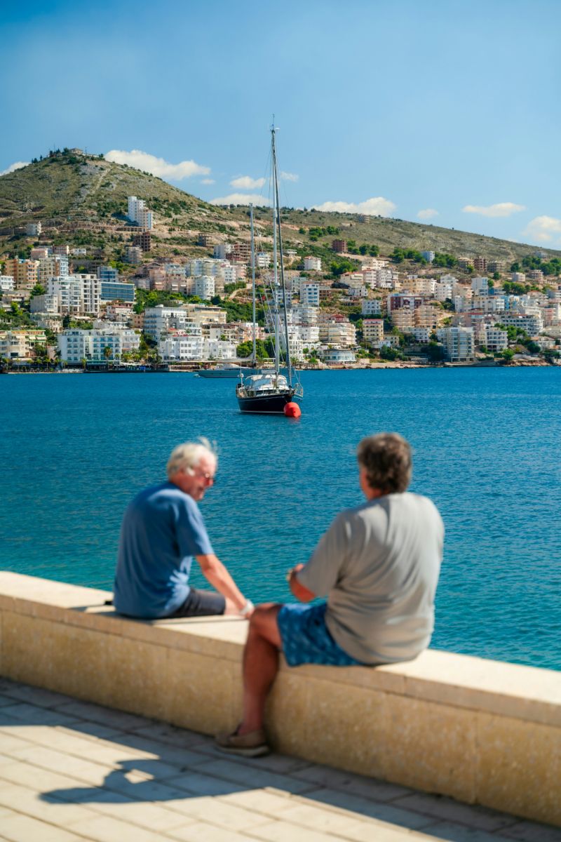men sitting along waterfront